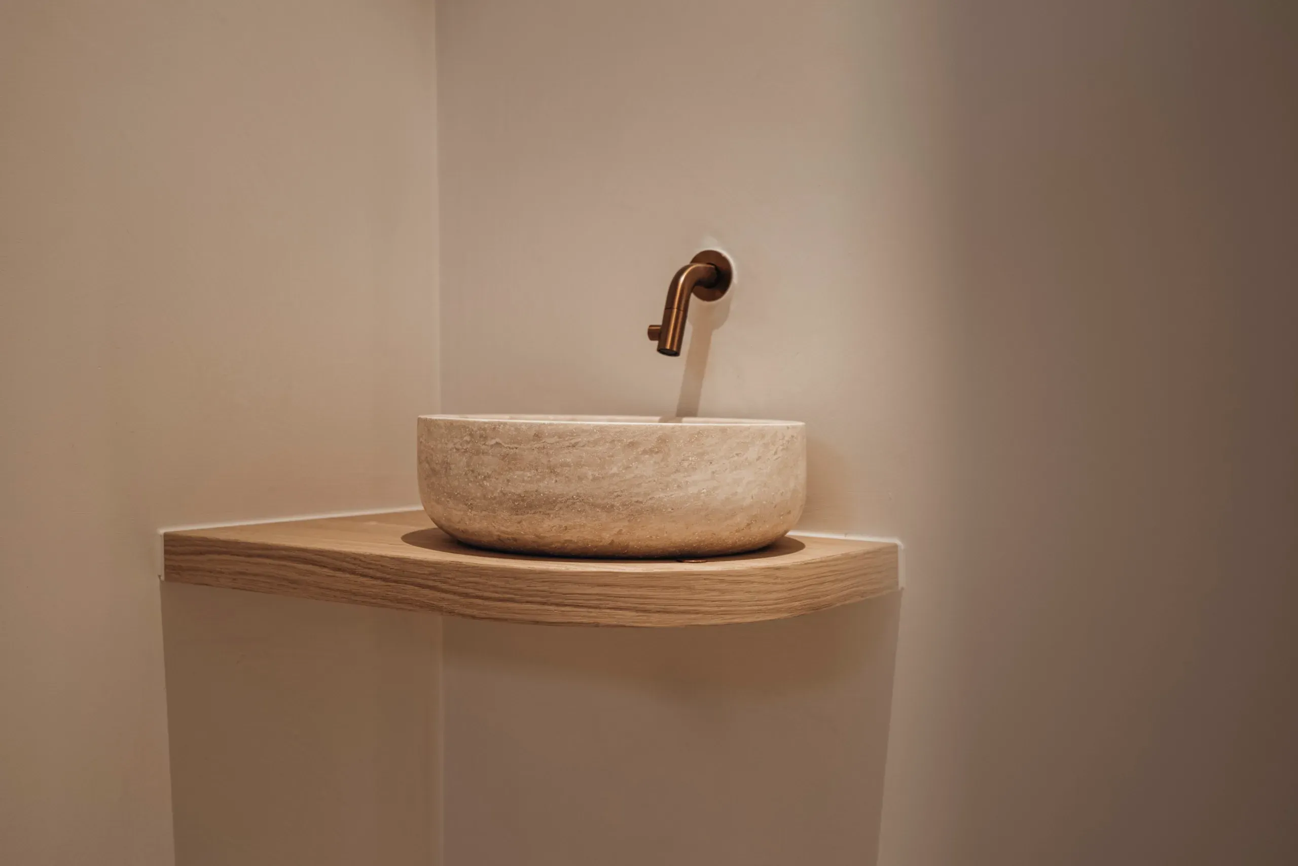 Natuurstenen waskom op een gebogen eiken plank in het toilet
