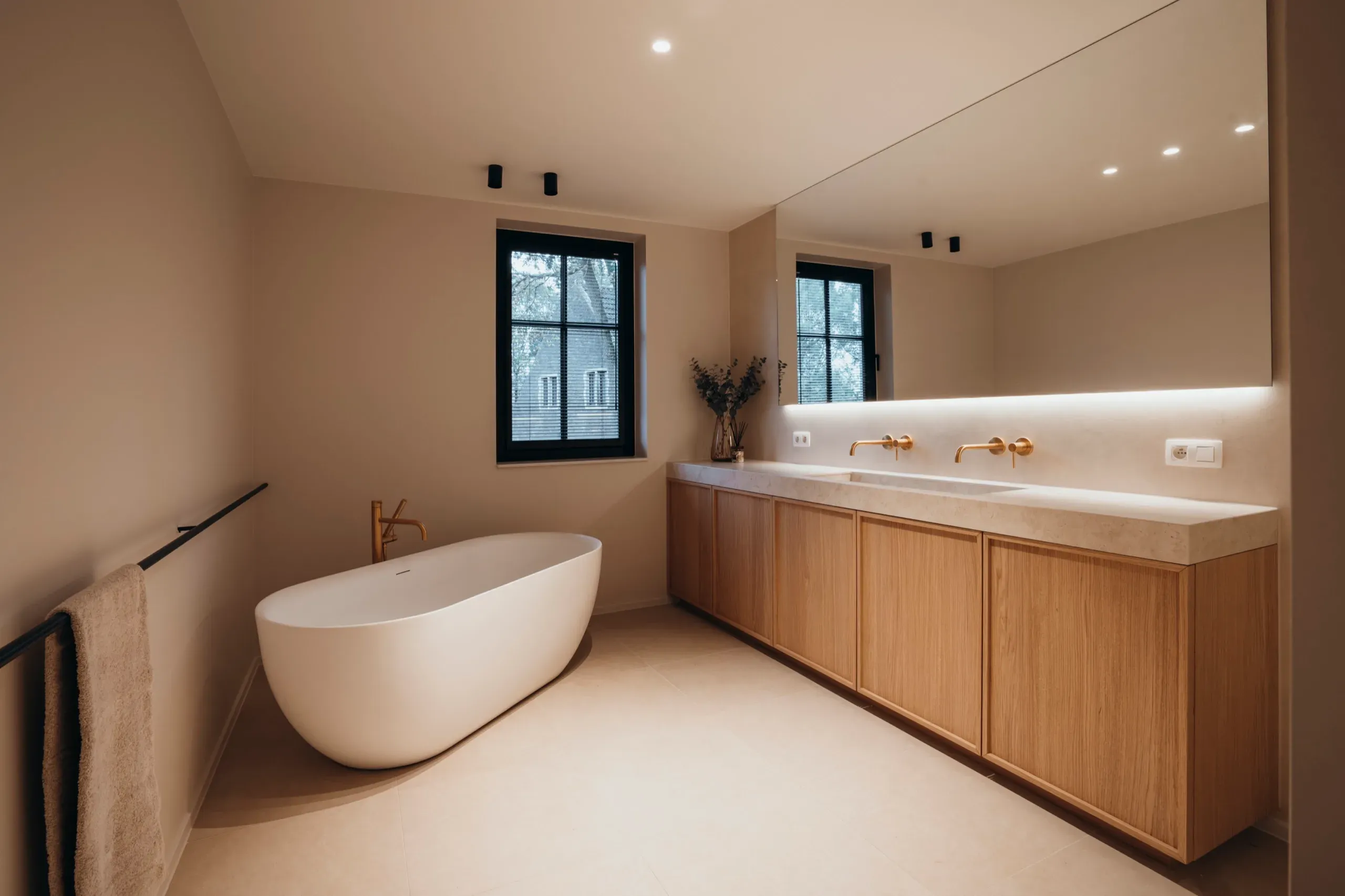 Badkamer met vrijstaand bad en eiken badkamermeubel met verlichte spiegel