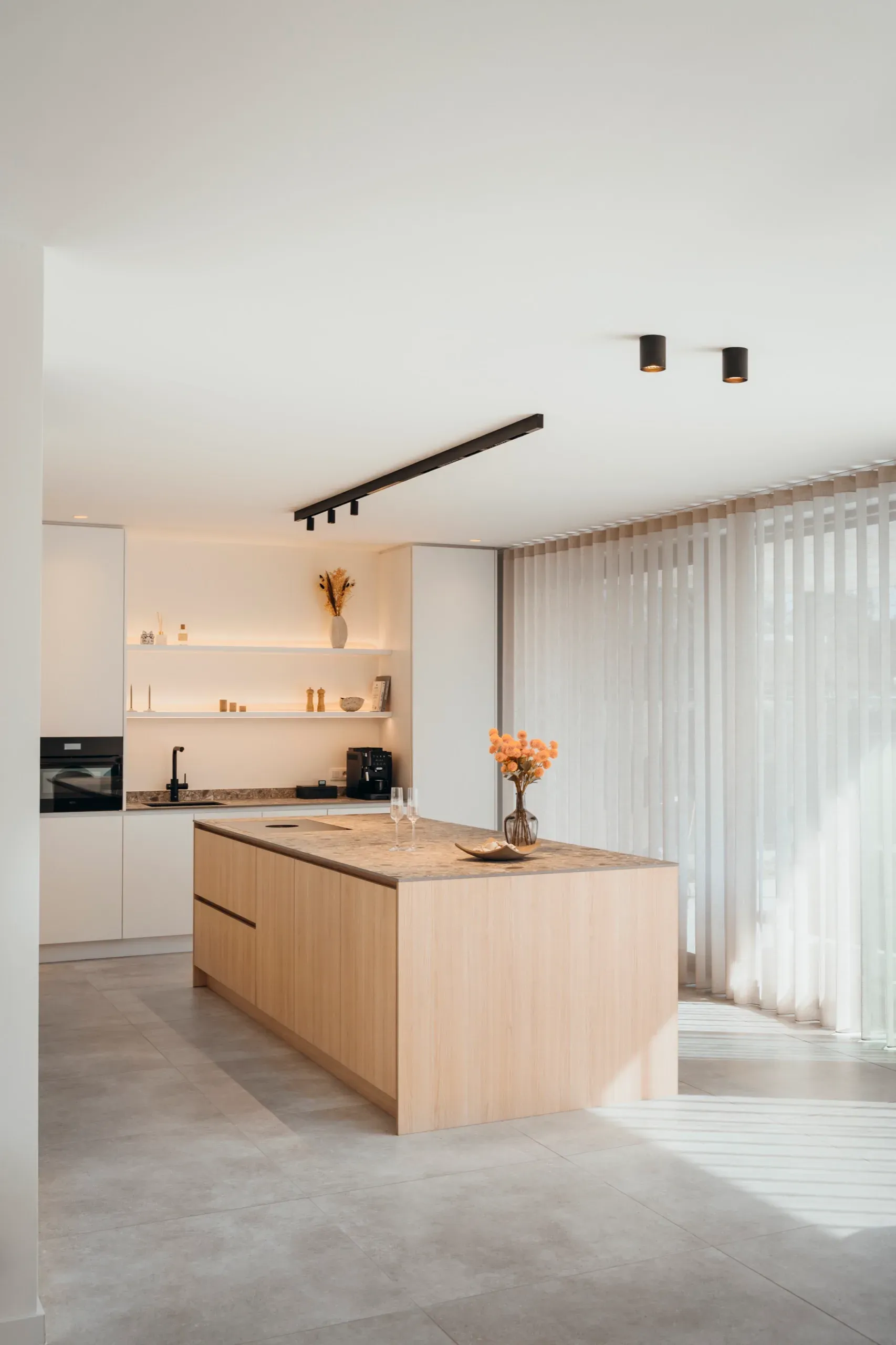 Zijaanzicht van de keuken met eiken eiland en witte kastenwand